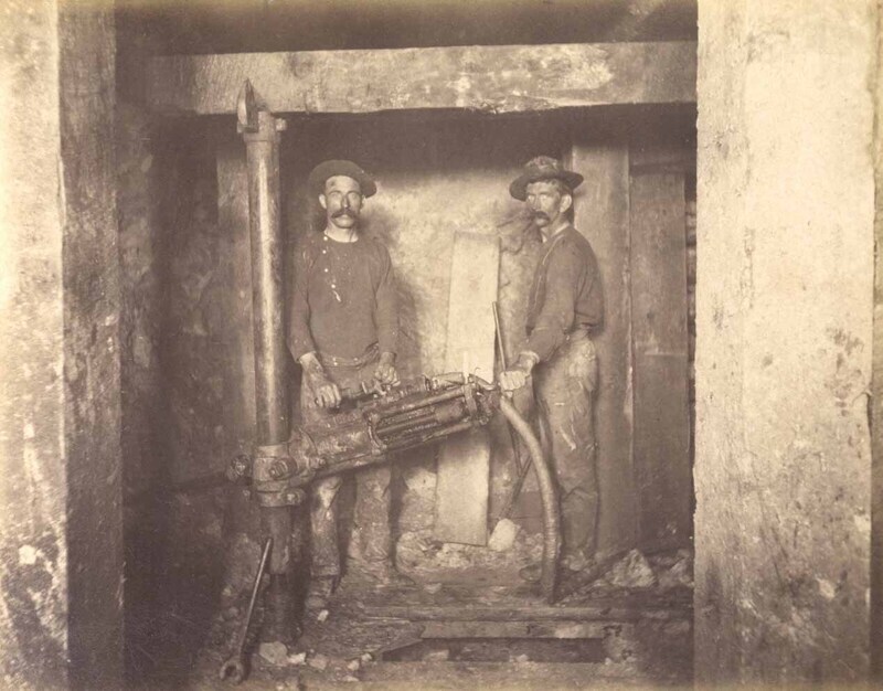 Mt Con 400 level East sill floor.  Ore breast showing miners drilling in ore.